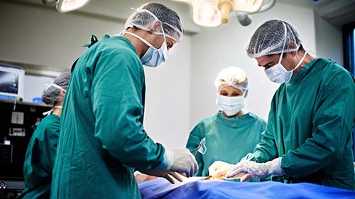 A SURGICAL TECHNOLOGIST HANDS A SURGEON THE PROPER SURGICAL INSTRUMENT